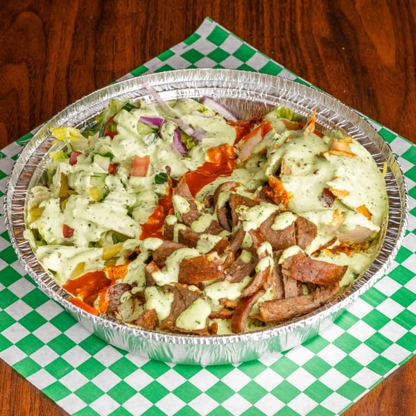A foil container of Leyla's Mediterranean Cafe's gyro meat, chicken, salad, and sauces on a checkered napkin.